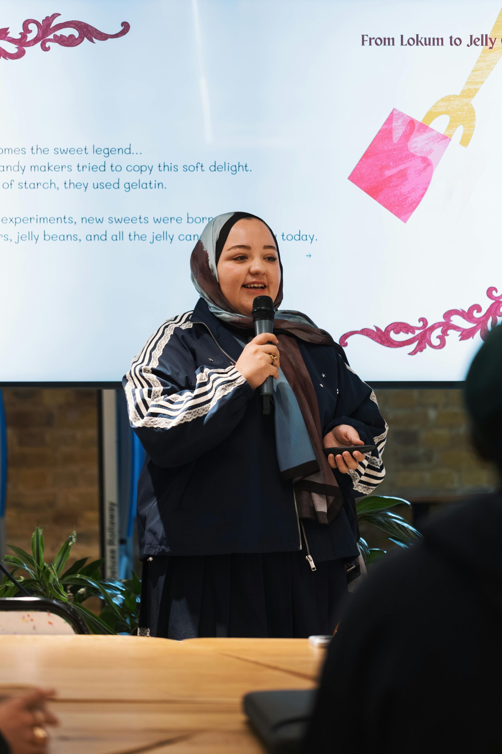 Woman presenting about traditional sweets with digital slideshow in a casual setting.